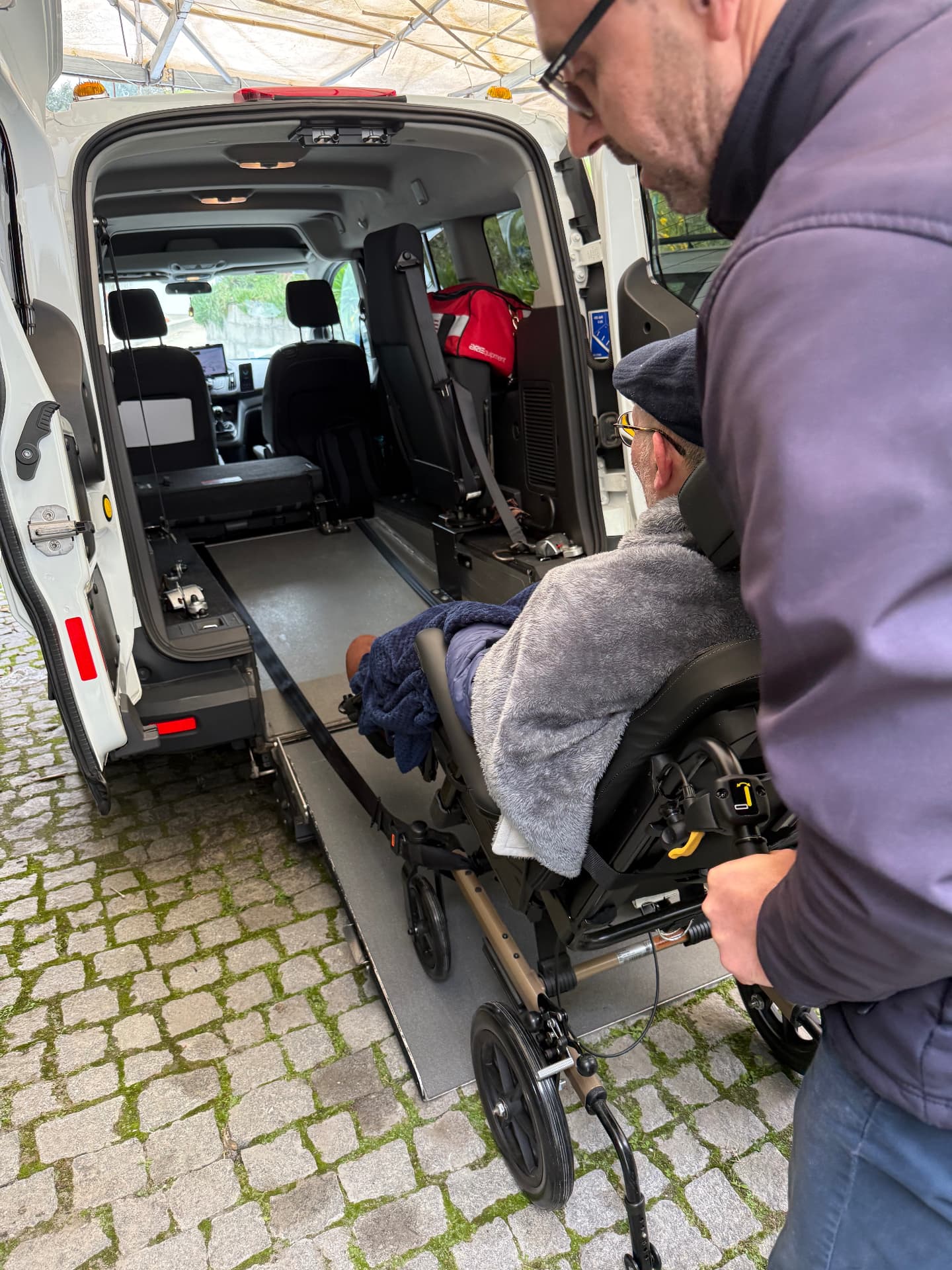 A caregiver helping Terry enter an accessible vehicle by wheelchair ramp